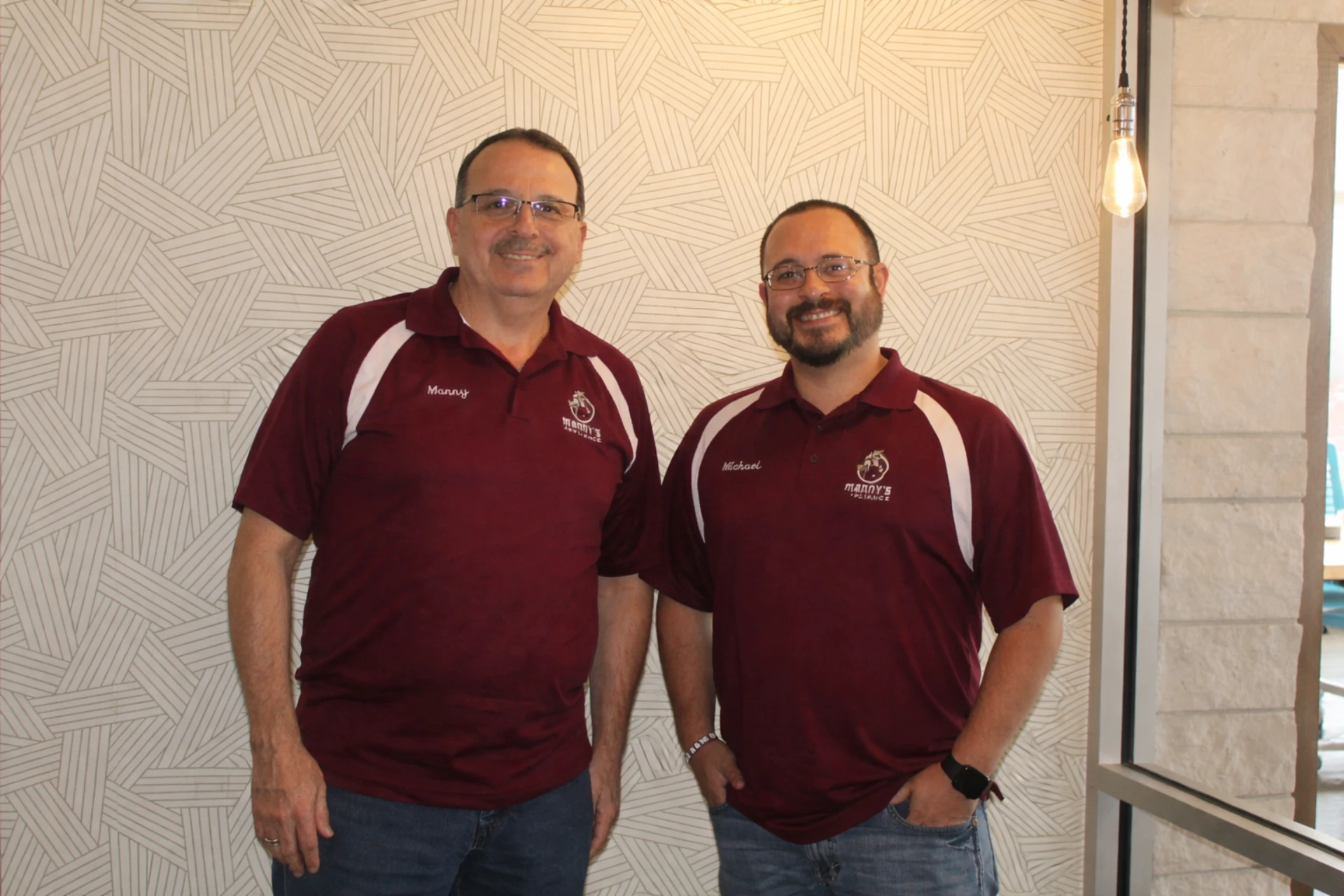 Two of Manny's Appliance's team standing next to each other wearing maroon uniforms